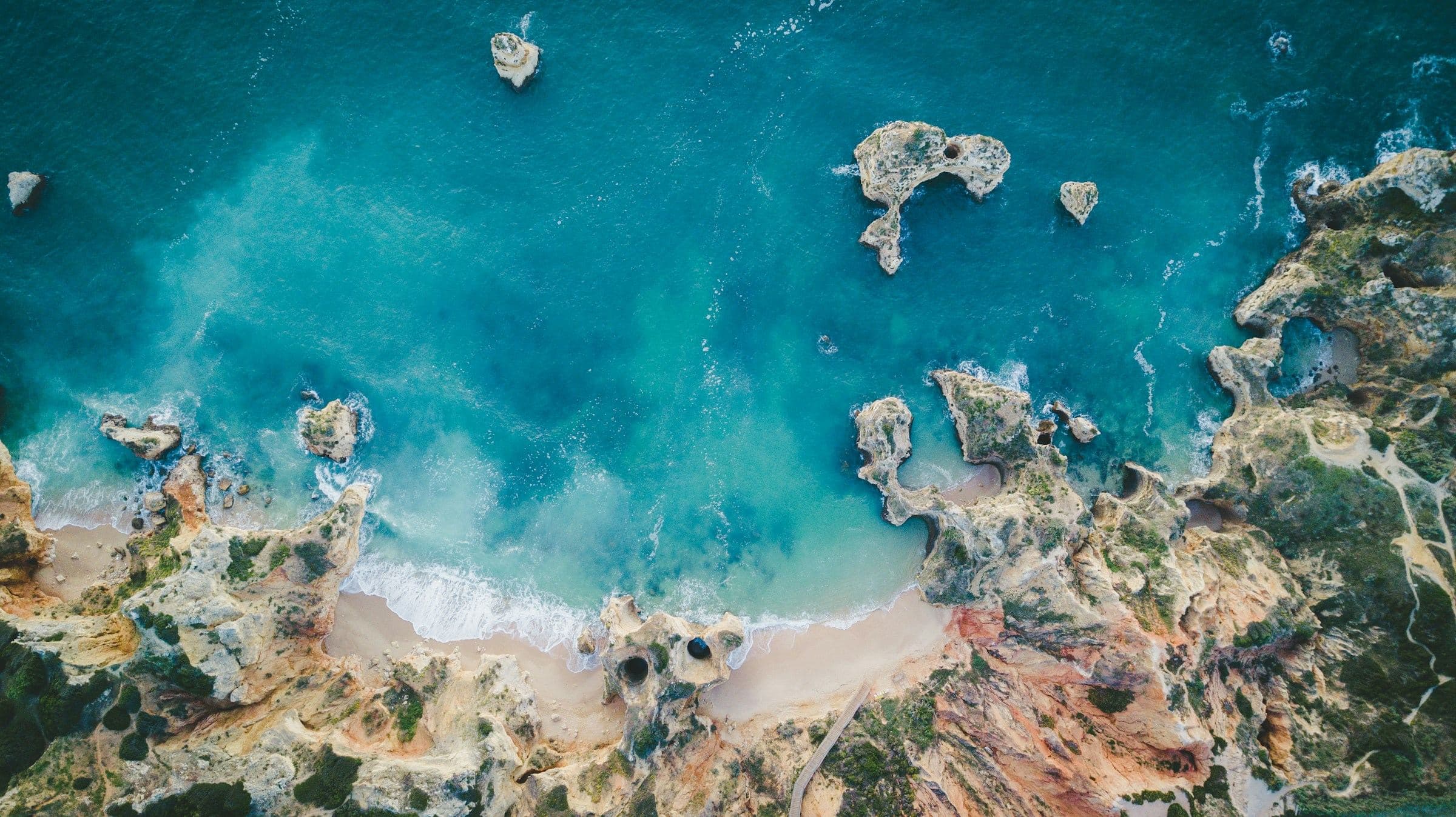 Vista aérea de la costa rocosa del Algarve cerca de Lagos, con acantilados y agua turquesa